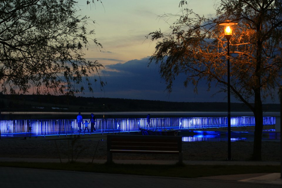 Świecący się w nocy pomost nad jeziorem w Dolsku